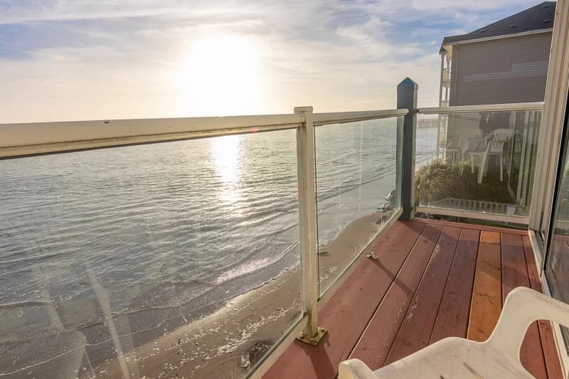 Wood balcony with glass railing facing a sunset ocean view in Lincoln City