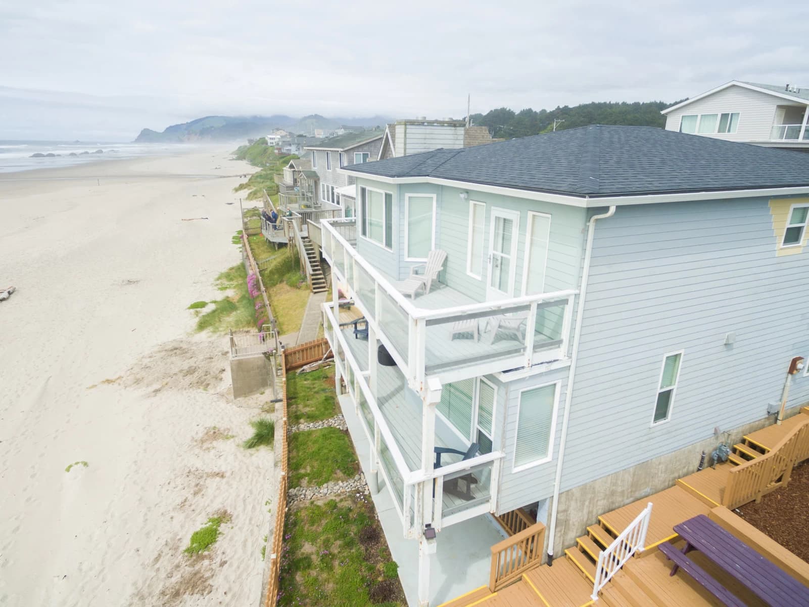 Light-blue beach house in Lincoln City with wraparound decks, white railings, and ocean