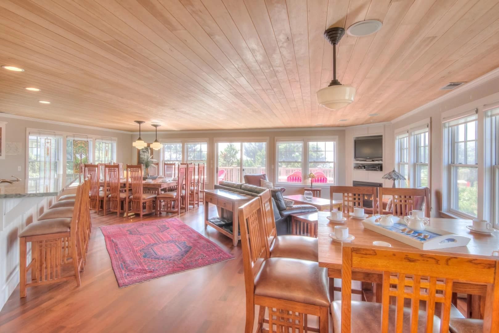 Open living-dining room in Lincoln City with wood ceiling, leather sofa, and red rug