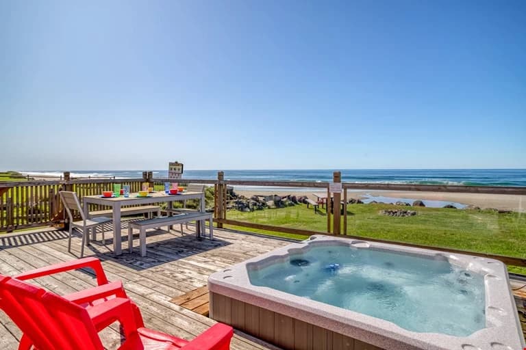 Oceanfront deck in Lincoln City with a square hot tub, red chairs, and gray dining table