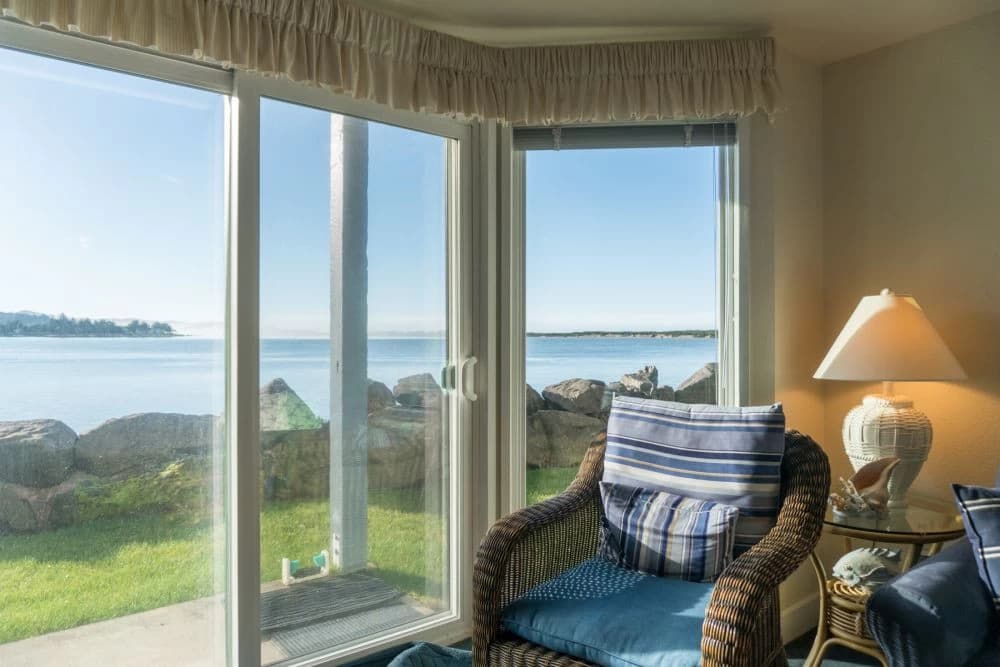 Wicker armchair with blue cushion facing bay views through glass doors in Lincoln City