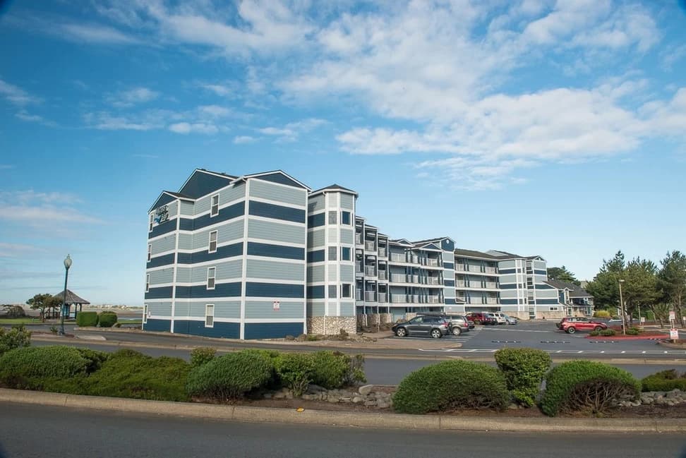 Blue-striped condo in Lincoln City with white trim, balconies, and a parking lot