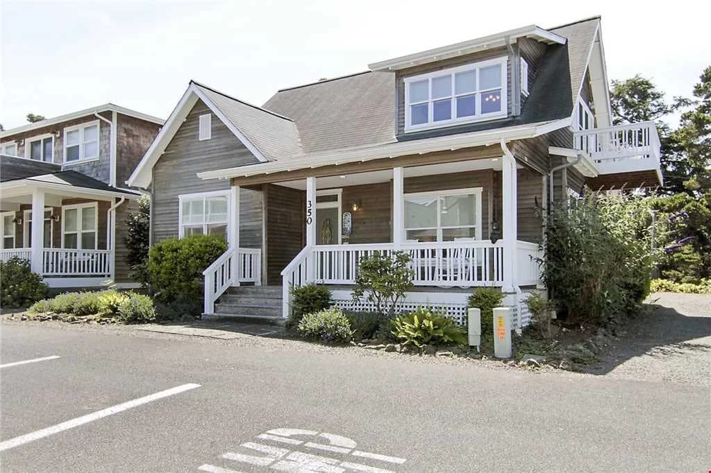Brown two-story cottage with white porch and side balcony in Depoe Bay