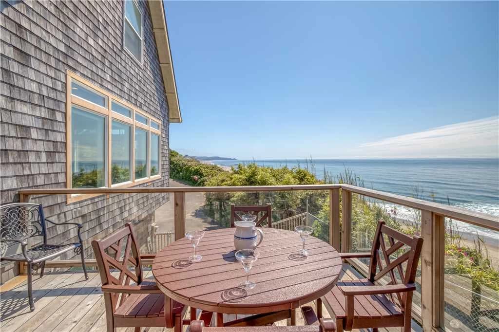 Cedar-shingle Lincoln City deck with a round table, pitcher, and wide ocean view