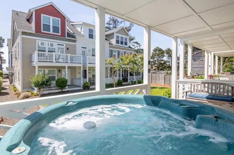Bubbling teal hot tub on a covered Depoe Bay porch facing neighboring beach houses