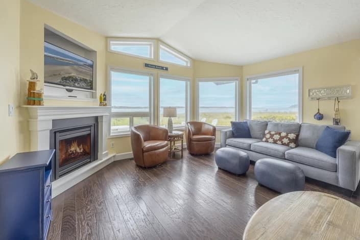 Lincoln City living room with a gray sofa, leather chairs, fireplace, and beach view