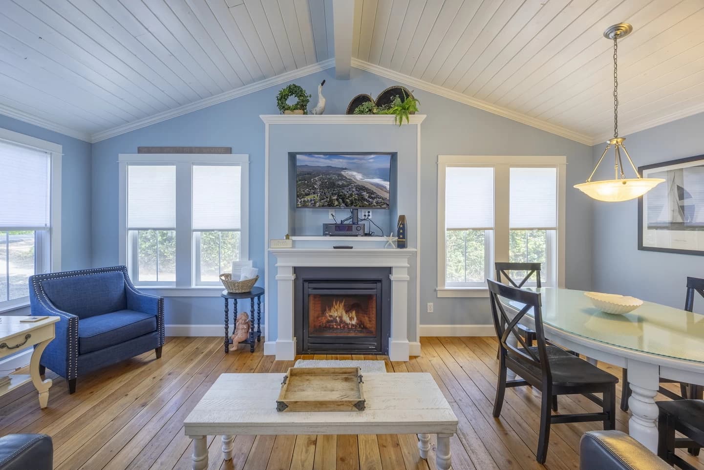 Lincoln Beach living room with light blue walls, fireplace, TV niche, and dining table