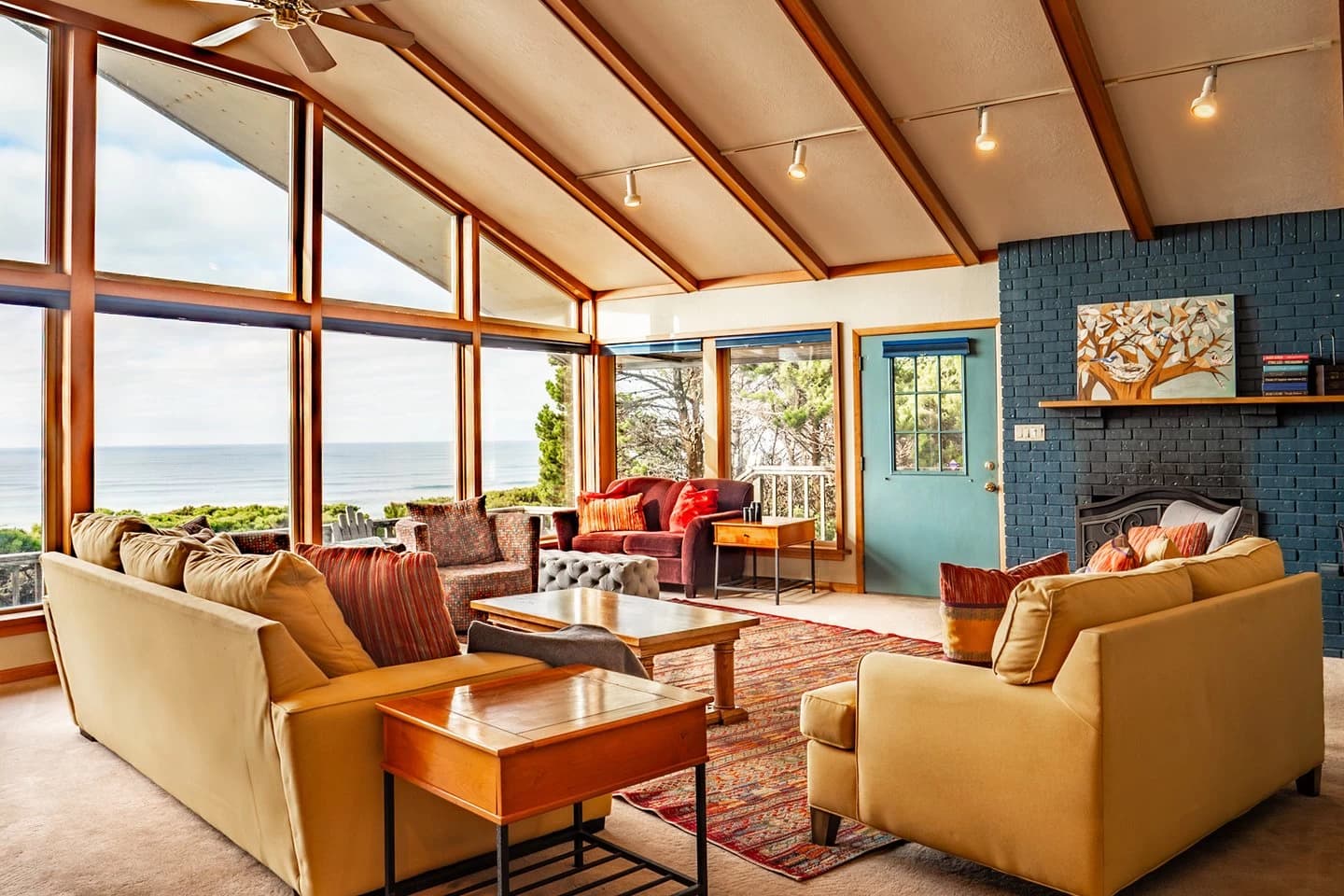 Living room in Newport with tan sofas, a blue brick fireplace, and ocean-view windows
